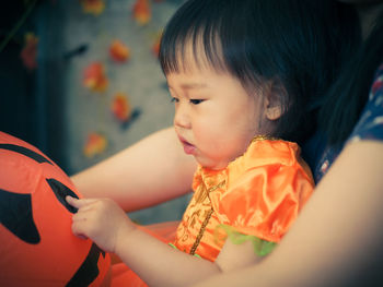 Midsection of woman sitting with daughter holding jack o lantern toy at home