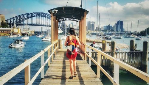 Woman on steps by bridge against sky