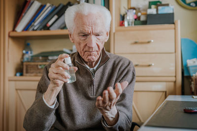 Senior man using hand sanitizer at home 