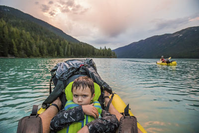 Young boy with grumpy face on a lake during paddling trip