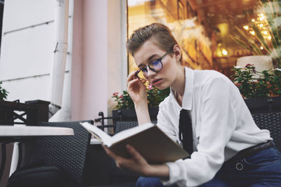 Young woman using mobile phone while sitting in cafe