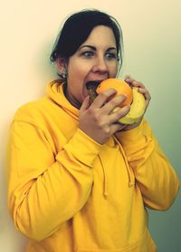 Young woman eating fruits against white background