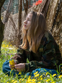 Teenager caucasian girl picking up flowers in springtime in a garden outdoors a sunny day