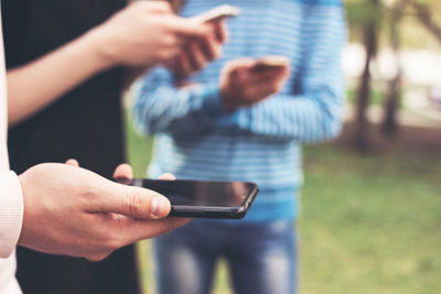 Close-up of friends using mobile phone outdoors