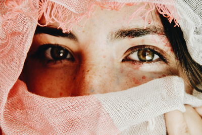 Close-up portrait of young woman covering face with fabric