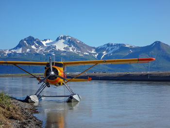 Scenic view of seaplane with snowcapped mountains against clear blue sky