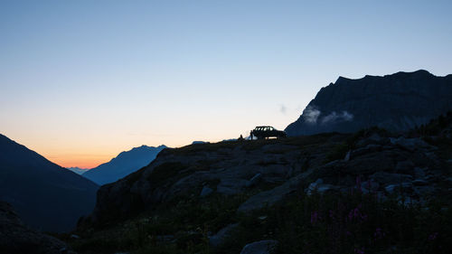 Silhouette rocks on mountain against sky during sunset