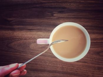 Directly above shot of hand holding tea cup on table