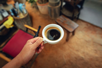 Cropped hand of woman holding coffee on table