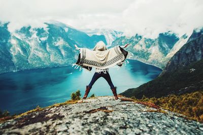 Rear view of person on rock against sky