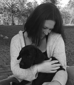 Rear view of woman with dog sitting outdoors