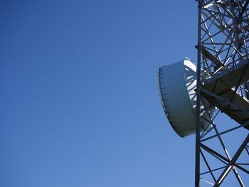 Low angle view of communications tower against clear blue sky