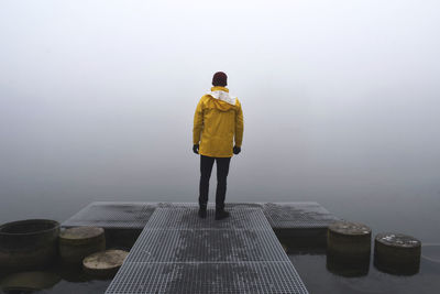 Rear view of man standing on jetty