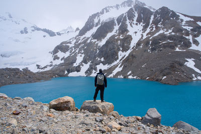 Rear view of man standing on rocks against mountain