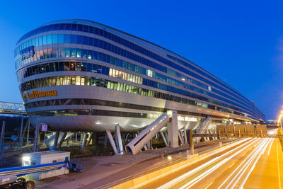 Light trails on road in city against blue sky