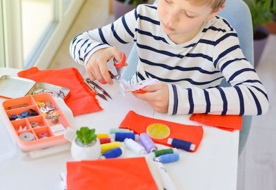 A caucasian boy  is learning to sew with his hands a homemade gift for mom for a holiday