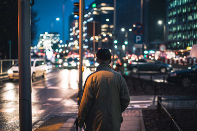 Rear view of a man walking on road at night