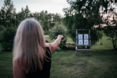 Rear view of woman photographing against trees