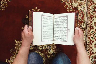 Midsection of man reading koran in mosque