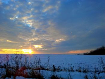 Scenic view of frozen field against sky during winter