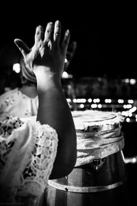 Cropped hand of woman playing drum at night