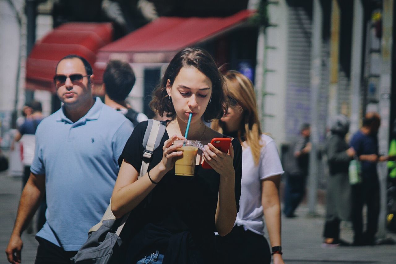 incidental people, young adult, real people, city, men, lifestyles, casual clothing, focus on foreground, group of people, front view, leisure activity, people, adult, three quarter length, holding, young men, drink, architecture, food and drink