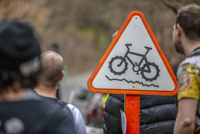 Rear view of man sitting on road sign