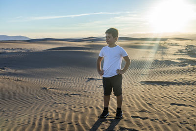 Full length of boy standing on sand at beach against sky