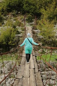 Rear view of woman walking on footbridge