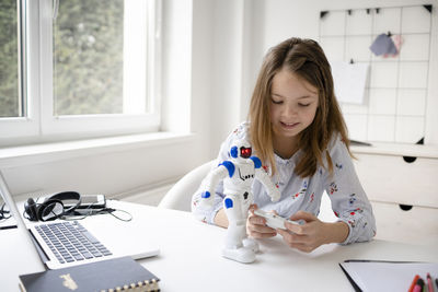 Girl looking away while sitting on table