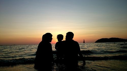 Silhouette of people on beach at sunset