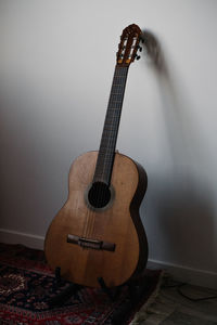 Close-up of guitar against wall at home