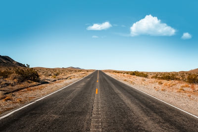 Empty road along landscape against sky