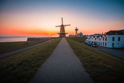 Buildings by sea against sky during sunset