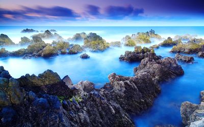 Panoramic view of rocks and sea against blue sky