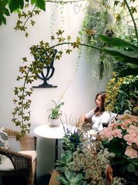 Woman sitting by potted plant on table