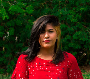 Portrait of young woman against trees