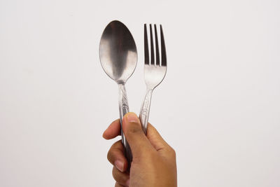 Close-up of hand holding object against white background