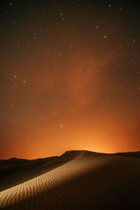 Scenic view of landscape against sky at night in the desert full of stars