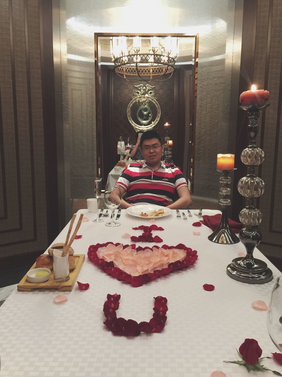 MAN SITTING ON TABLE IN ILLUMINATED HOME