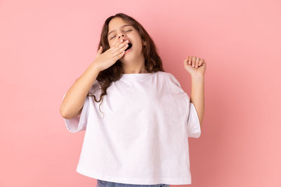 Young woman standing against pink background