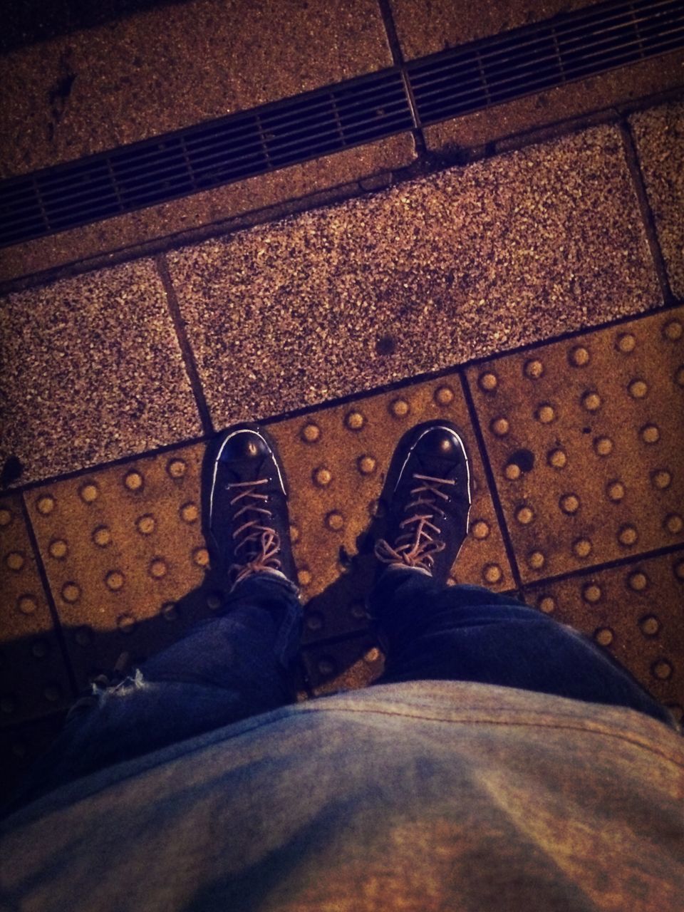 low section, person, shoe, personal perspective, standing, high angle view, footwear, lifestyles, human foot, street, jeans, men, leisure activity, road, shadow, sidewalk, paving stone