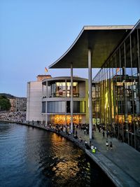 Modern building on a river side with water reflection during sunset