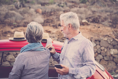 Senior couple standing by car