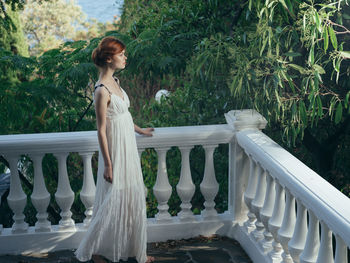 Side view of woman standing by railing