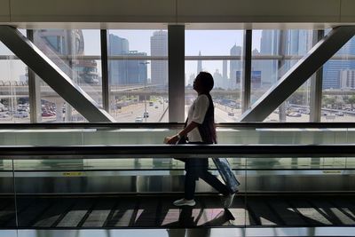 Full length of woman standing by railing in airport