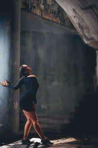 Full length of young woman standing in abandoned house