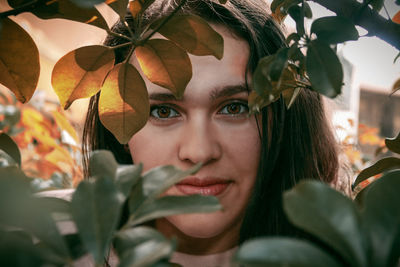 Close-up portrait of young woman with leaves