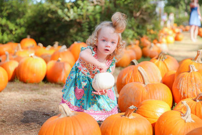 Portrait of smiling boy with pumpkins on field during autumn