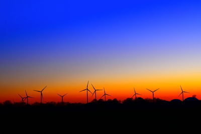 Silhouette of wind turbine against clear sky during sunset